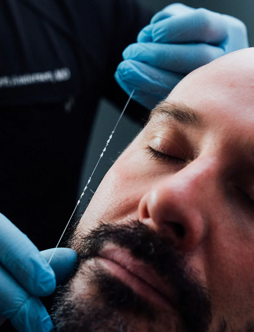 A close up shot of Dr. Craft measuring a male patients face with a thin thread. The photo only shows the clients face with his eyes closed and Dr. Crafts hands. - Instalift for Men in Phoenix, AZ